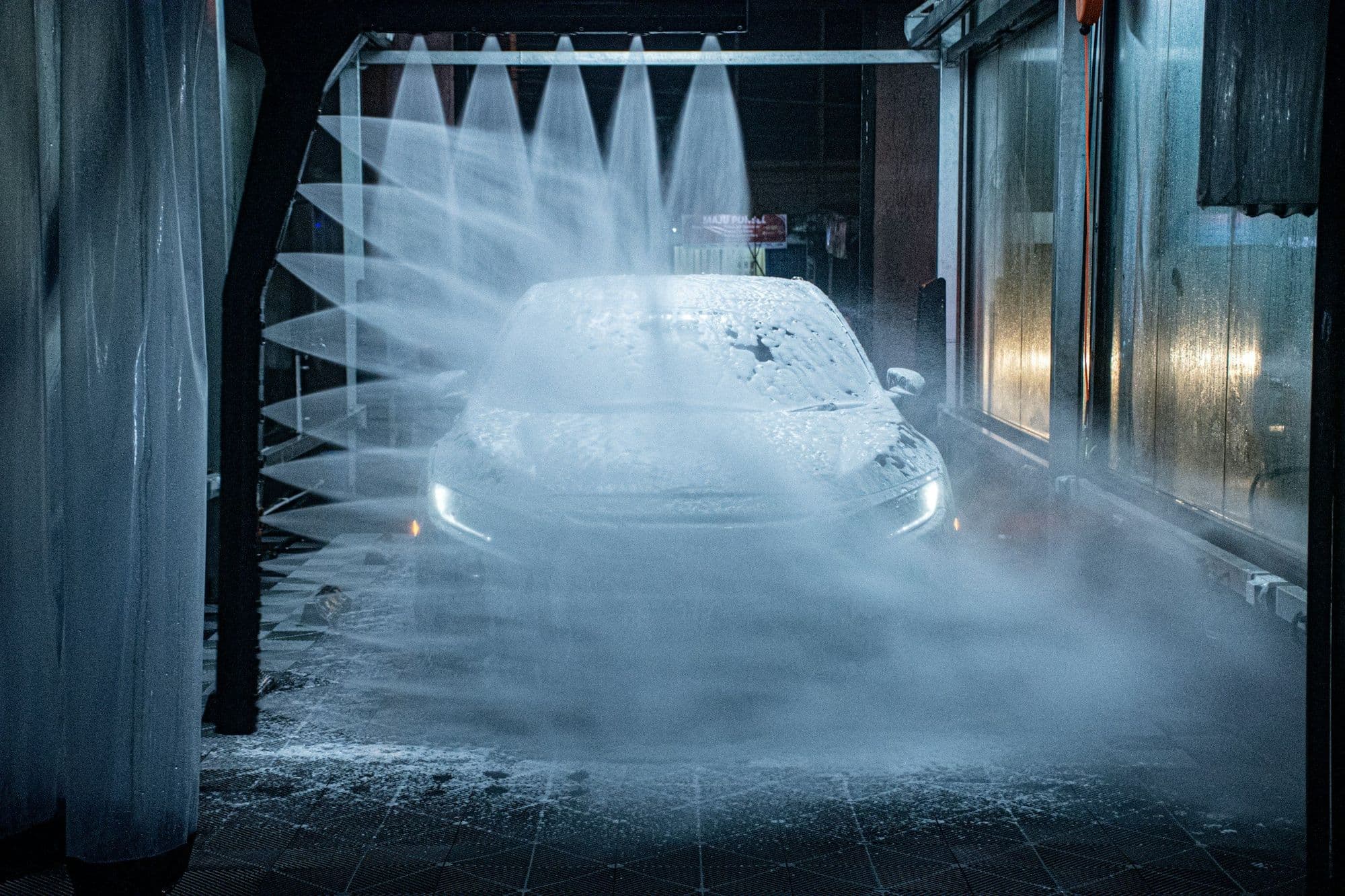 A car moving through the wash tunnel under the rinse arch